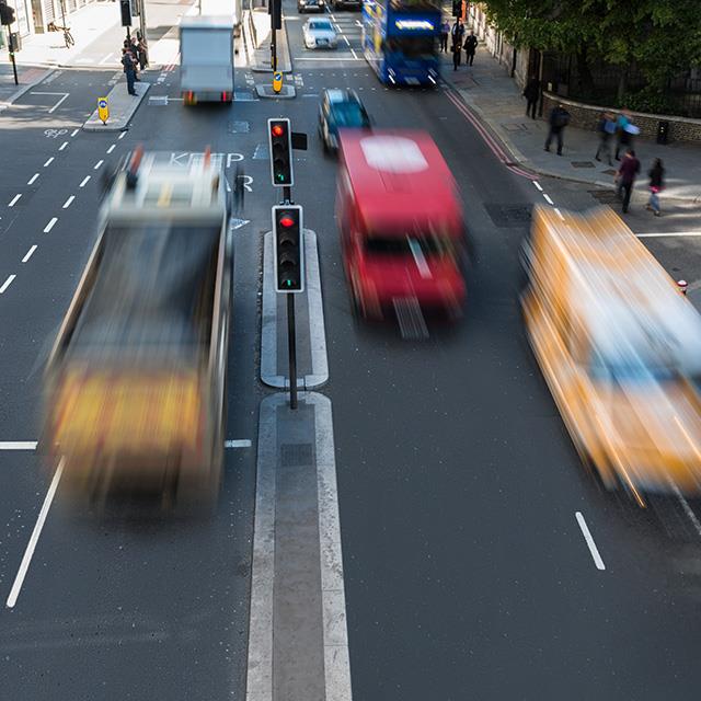 traffic on a busy city street three vehicles in foreground blurred